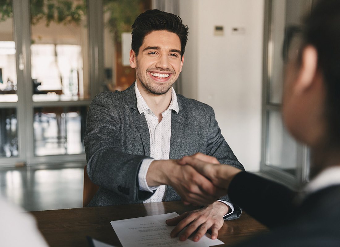 Join Our Team - Portrait of a Cheerful Young Man Wearing a Suit Shaking Hands with a Hiring Manager During an Interview